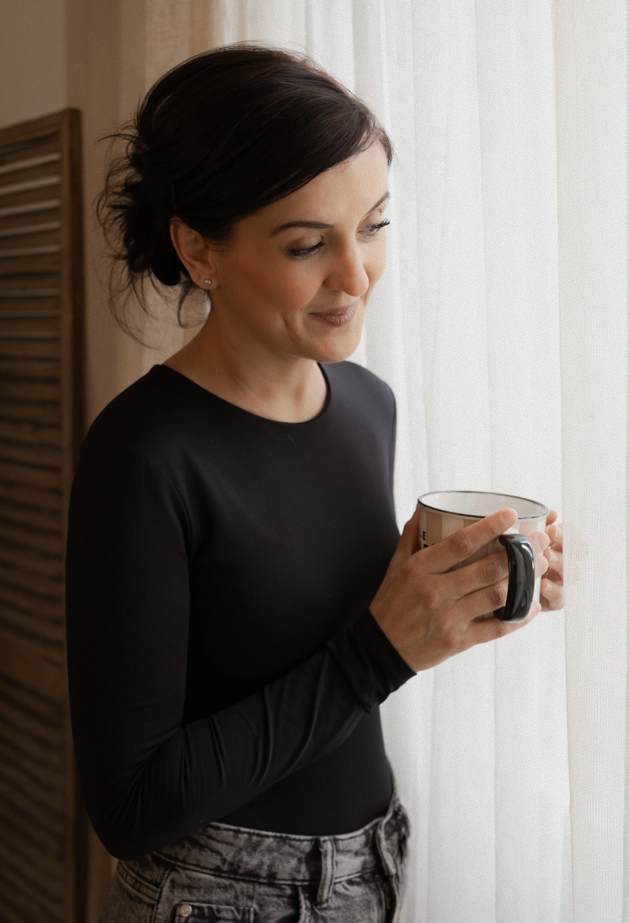 Christelle Lang, coach de vie intégrative spécialisée en hypersensibilité, dans un moment de calme avec une tasse près d’une fenêtre